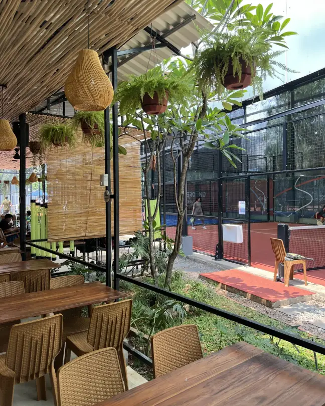 Café tables under a bamboo ceiling beside the courts